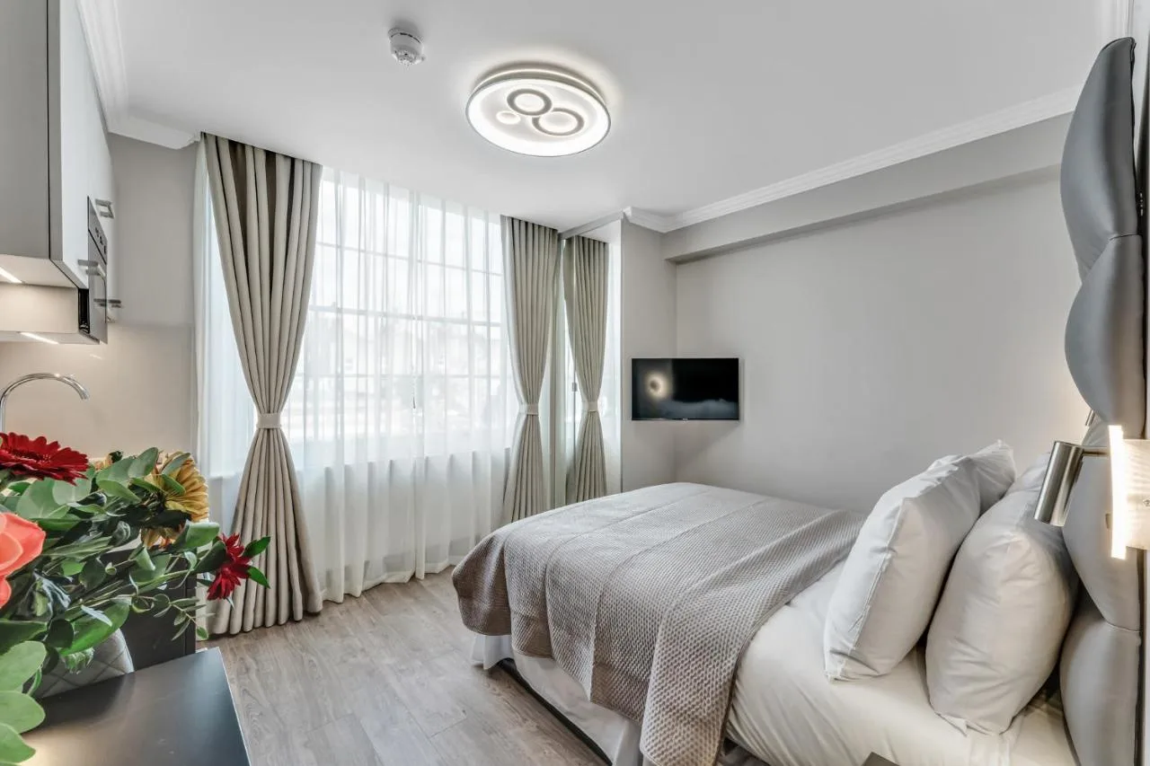 White bedroom with bed and window at Cleveland Residences Bloomsbury